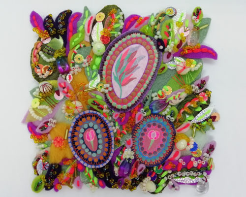 A colourful abstract textile artwork on a small canvas panel which measures just over 4 inches on each side. It's full of vibrant pink, green and purple shades of threads and fabrics which have been handstitched together to create a decorative and patterned landscape. 3 concentric circles contain pink petaled flowers and leaves in the middle. The circular shapes are surrounded by all the intricate textiles. It's full of sparkly beads and sequins, and is very textured to the touch, with hints of yellow in it